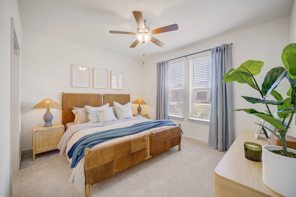 A bedroom with a bed, nightstands, and a ceiling fan.