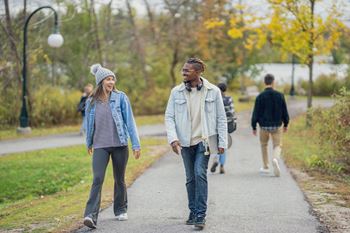 A man and a woman are walking down a path in a park.