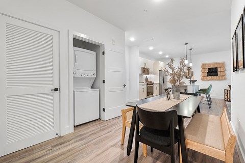 A kitchen with a table and chairs in the foreground and a refrigerator in the background.
