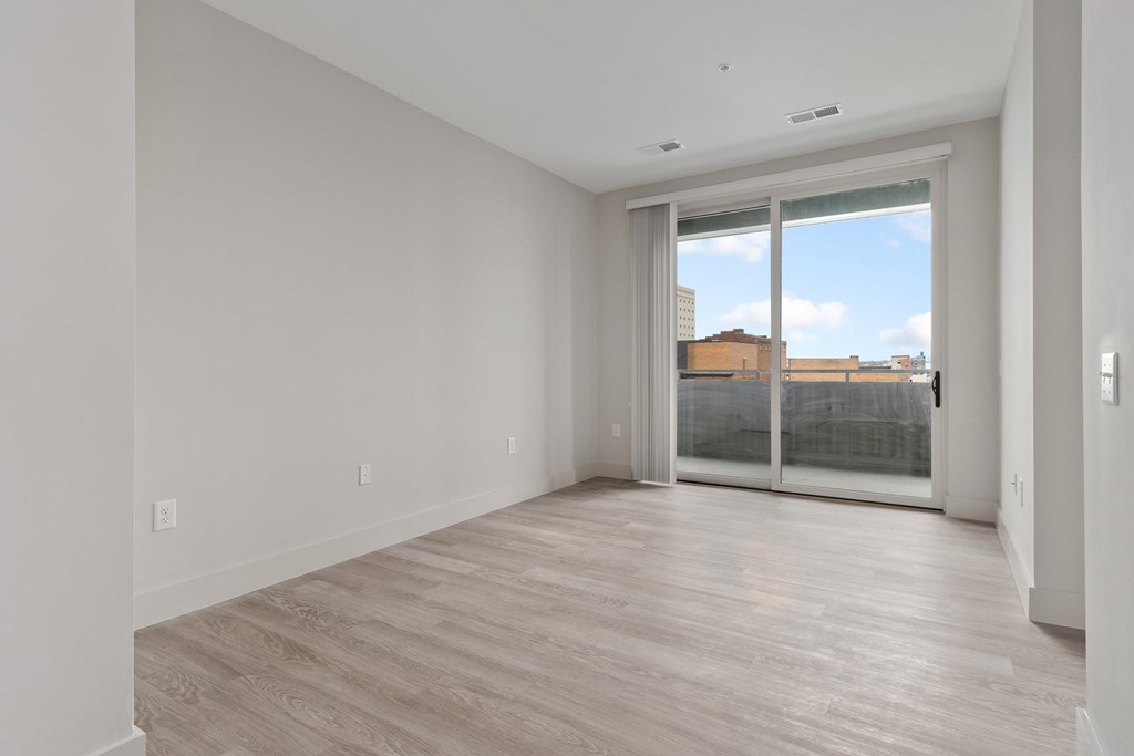 A room with a sliding glass door leading to a balcony.