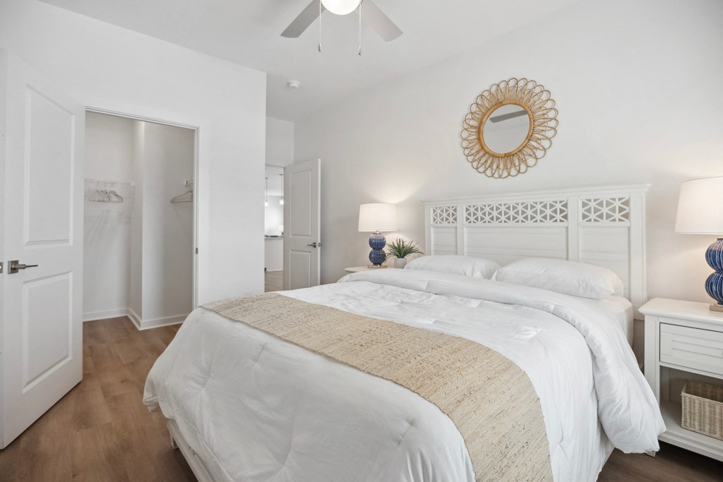a white bedroom with a large bed and a mirror