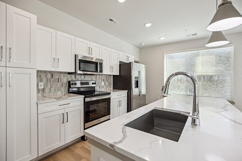 A modern kitchen with white cabinets and a marble backsplash.