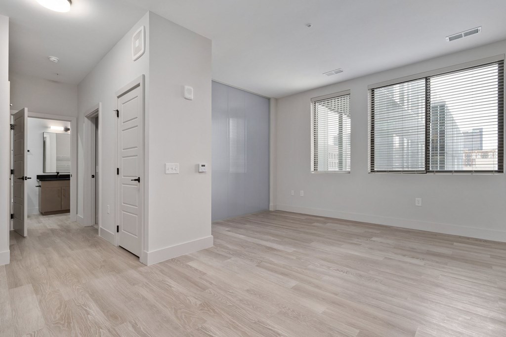A spacious room with light wood flooring and white walls.