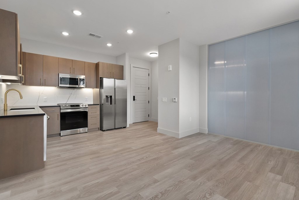 A modern kitchen with wooden cabinets and a stainless steel refrigerator.