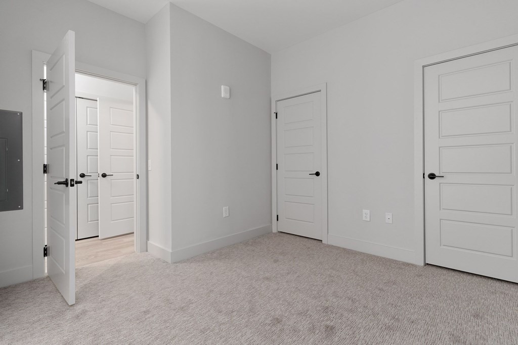 A white room with three doors and a carpeted floor.