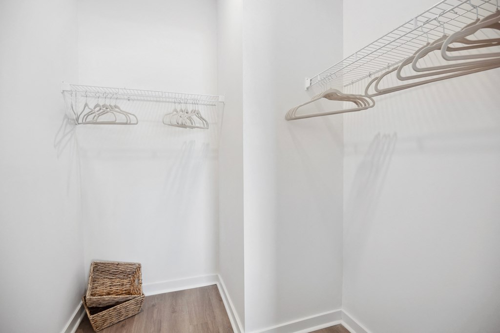 a walk in closet with white walls and a closet organizer and a wicker basket