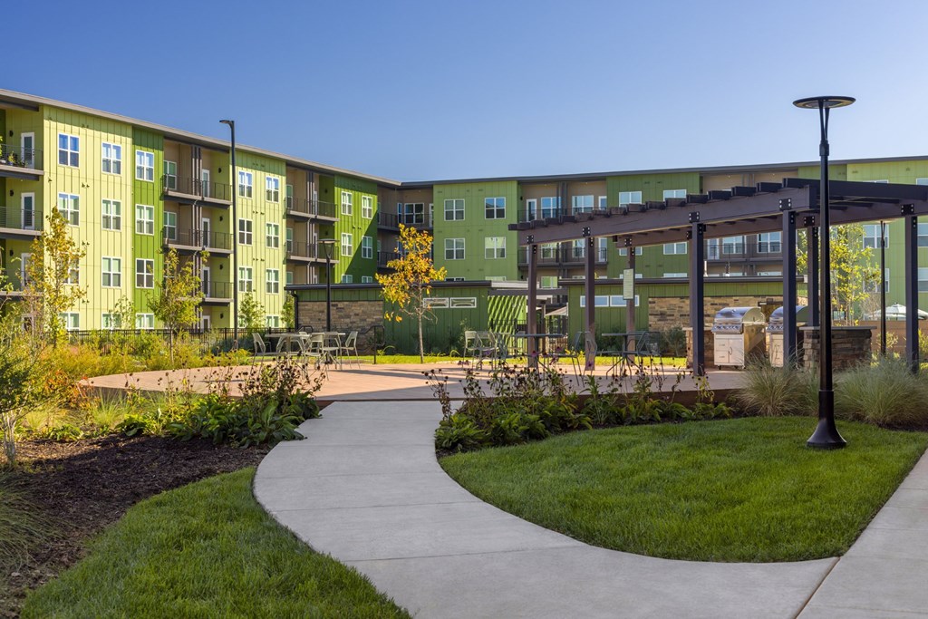 A walkway leads through a grassy area in front of apartment buildings.