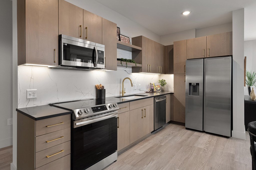 A modern kitchen with a black countertop and stainless steel appliances.