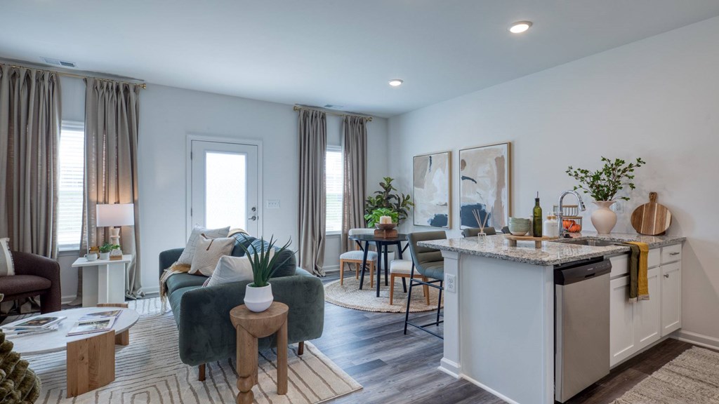 A modern kitchen with a green couch and a dining table at The Mark Townhomes Apartments, Harrisonburg, VA