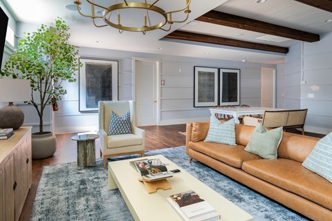 A living room with a brown couch and a chandelier.