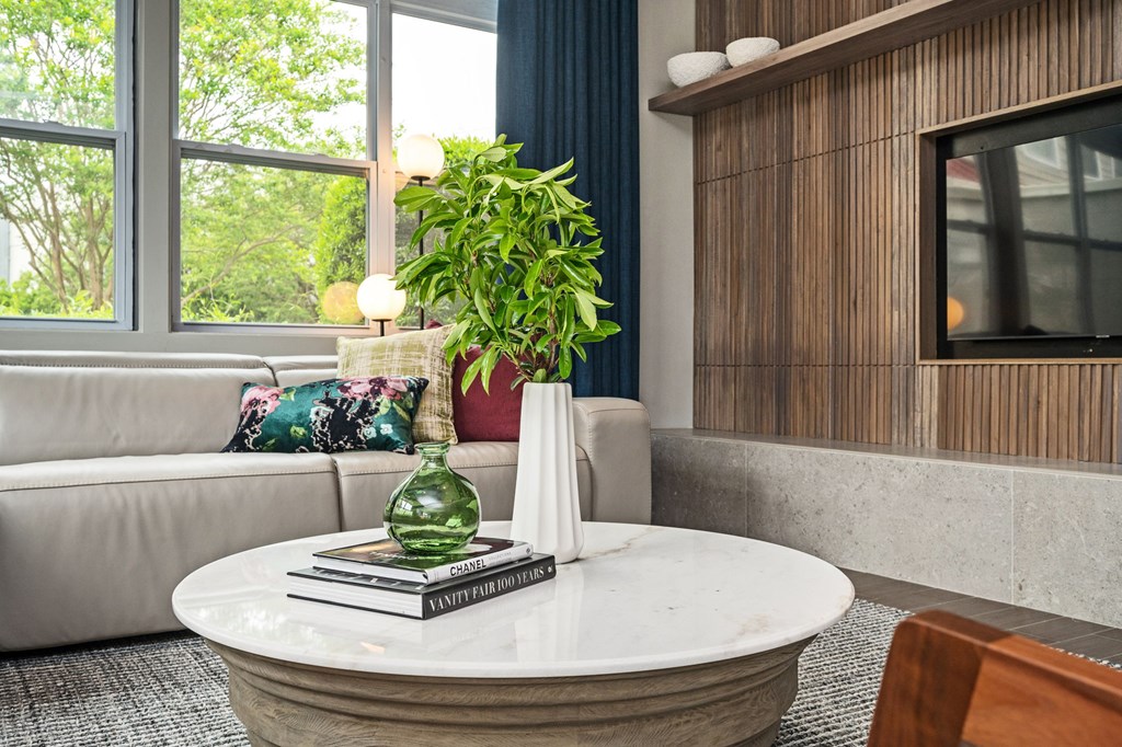 A living room with a white table and a green vase on it.