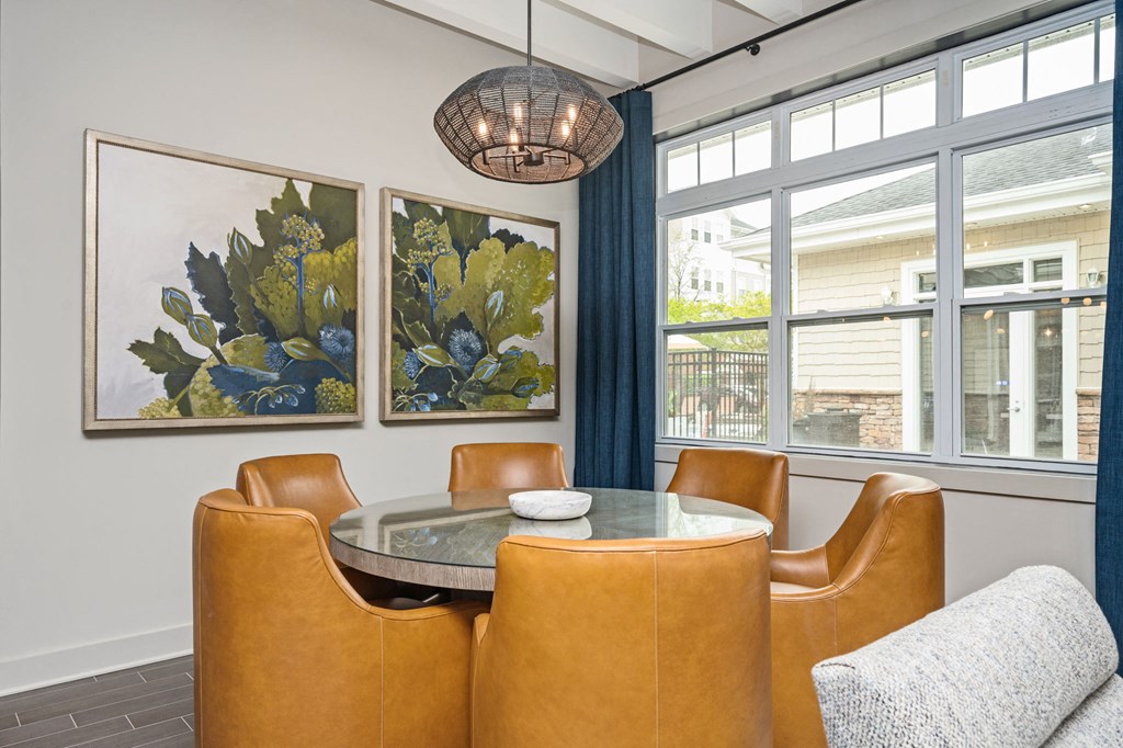 A dining room with a table surrounded by chairs and two paintings on the wall.