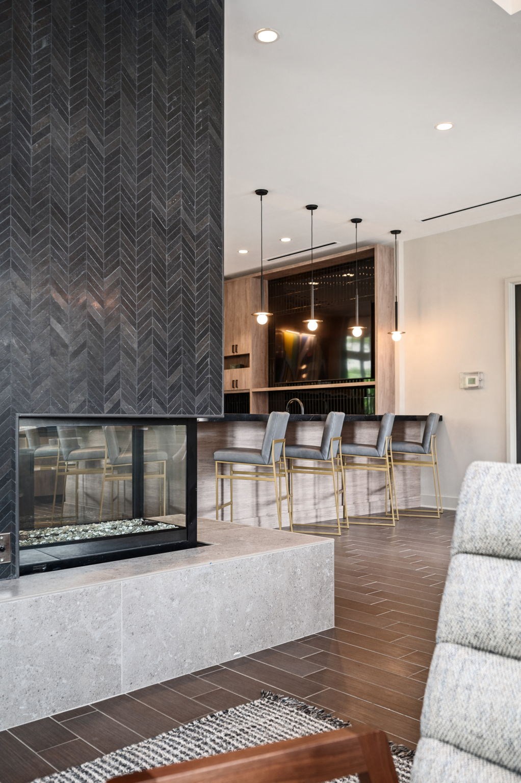 A modern living room with a fireplace and a herringbone patterned column.