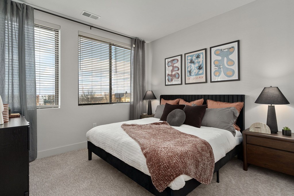 A bedroom with a large bed and a window with curtains.