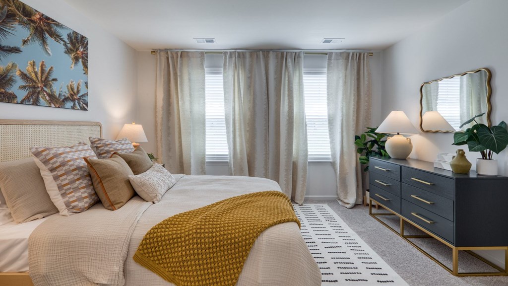 A bedroom with a large bed, a dresser, and a mirror at The Mark Townhomes Apartments, Harrisonburg, VA, 22801