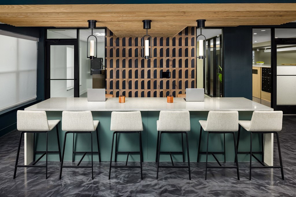 A modern bar with white stools and a wooden backdrop.