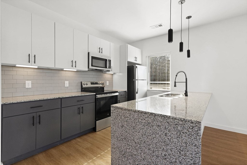 A kitchen with a granite countertop and dark grey cabinets. at Terraces at High Mountain, Alabama, 35811