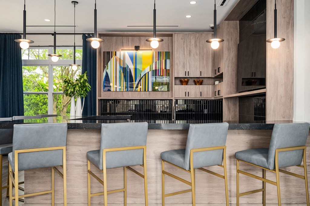 A modern bar area with grey chairs and a wooden counter.