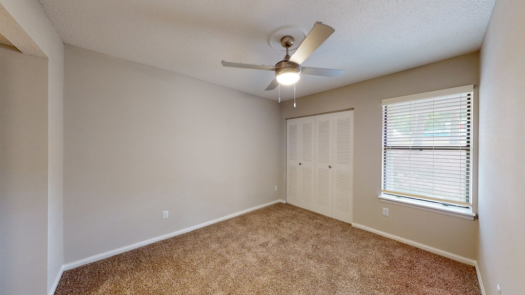 a bedroom with a ceiling fan and window