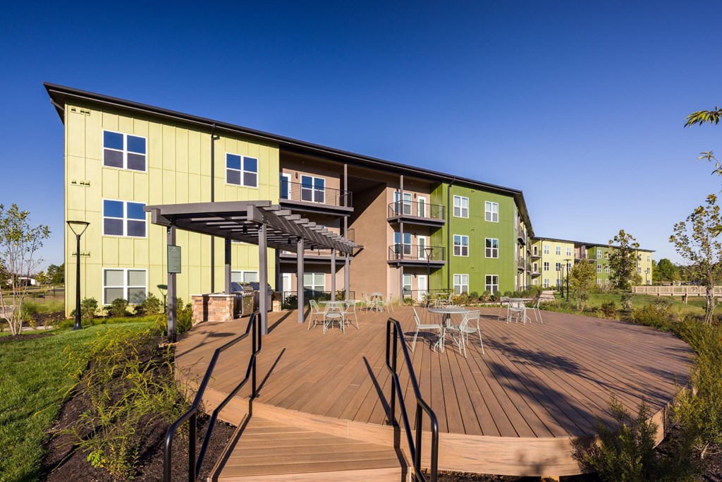 A modern building with a green and yellow exterior and a wooden deck in front.