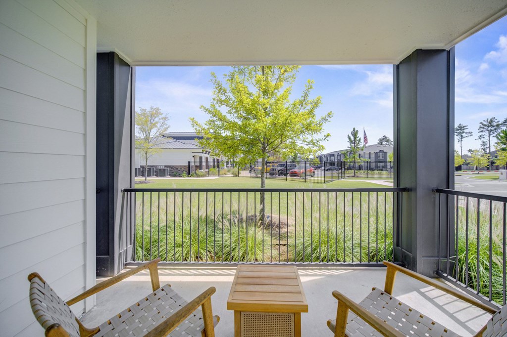 A balcony with a table and chairs overlooking a green lawn.