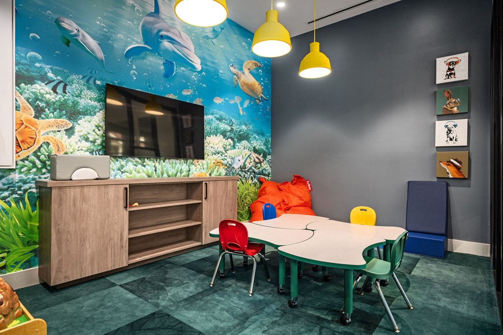 A room with a table, chairs and a mural of dolphins.