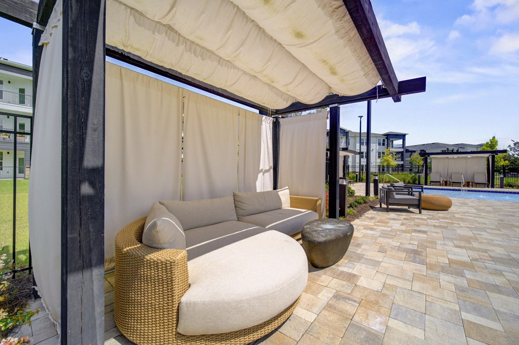 A patio with a couch and a table under a canopy.