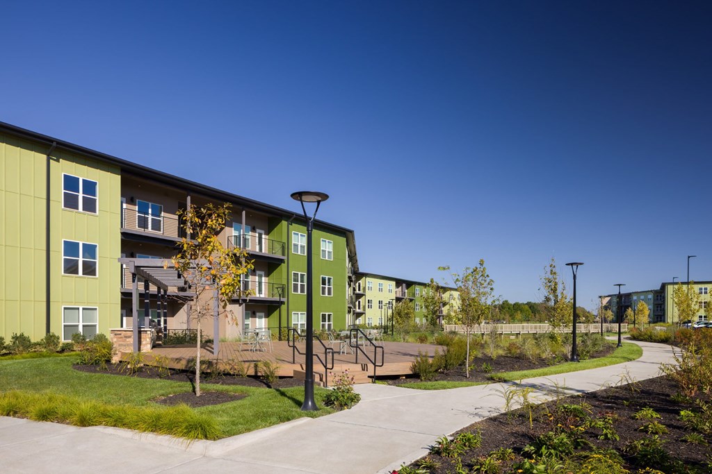 A green apartment complex with a clear blue sky in the background.