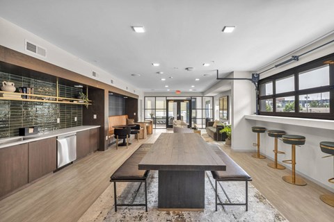 A modern kitchen with a long wooden table in the middle.