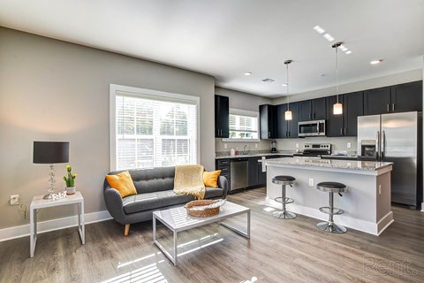 A modern kitchen and living room with a grey couch and a coffee table.