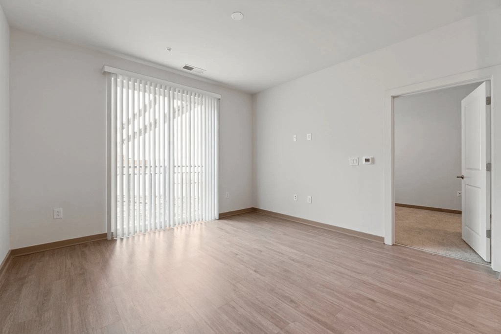 spacious living room with wood flooring and sliding glass door to bedroomat Metropolis Apartments, Glen Allen