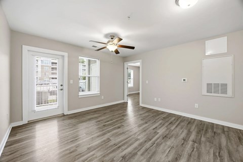 A spacious room with a ceiling fan and wooden flooring.