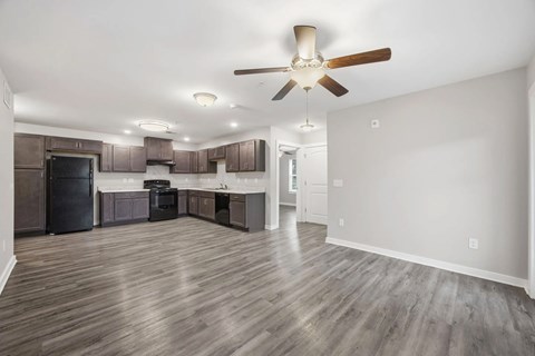 A spacious kitchen with dark wood floors and a ceiling fan.