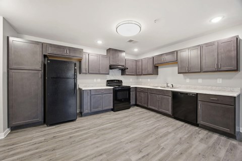 A kitchen with dark wood cabinets and a black refrigerator.