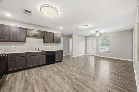 A kitchen with wooden floors and dark brown cabinets.