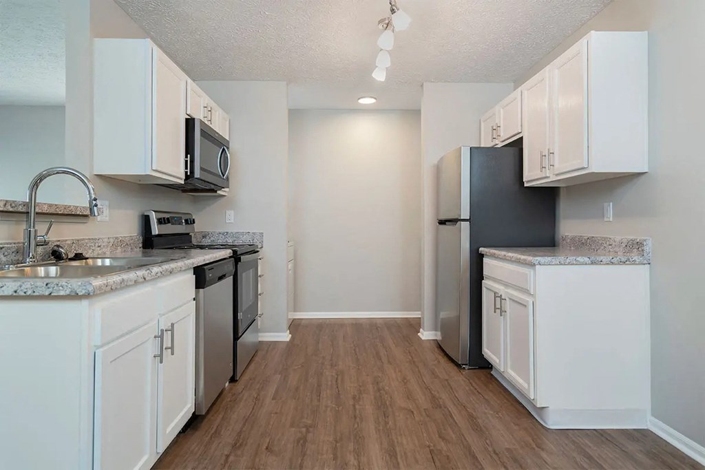 A kitchen with white cabinets and a black refrigerator.