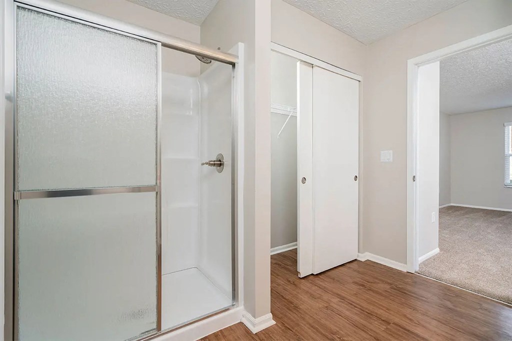 A white door with a glass panel is open to a room with wood flooring.