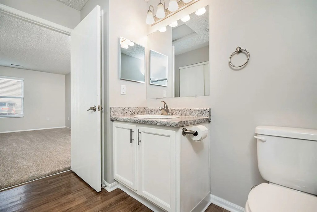 A white bathroom with a toilet, sink, and mirror.