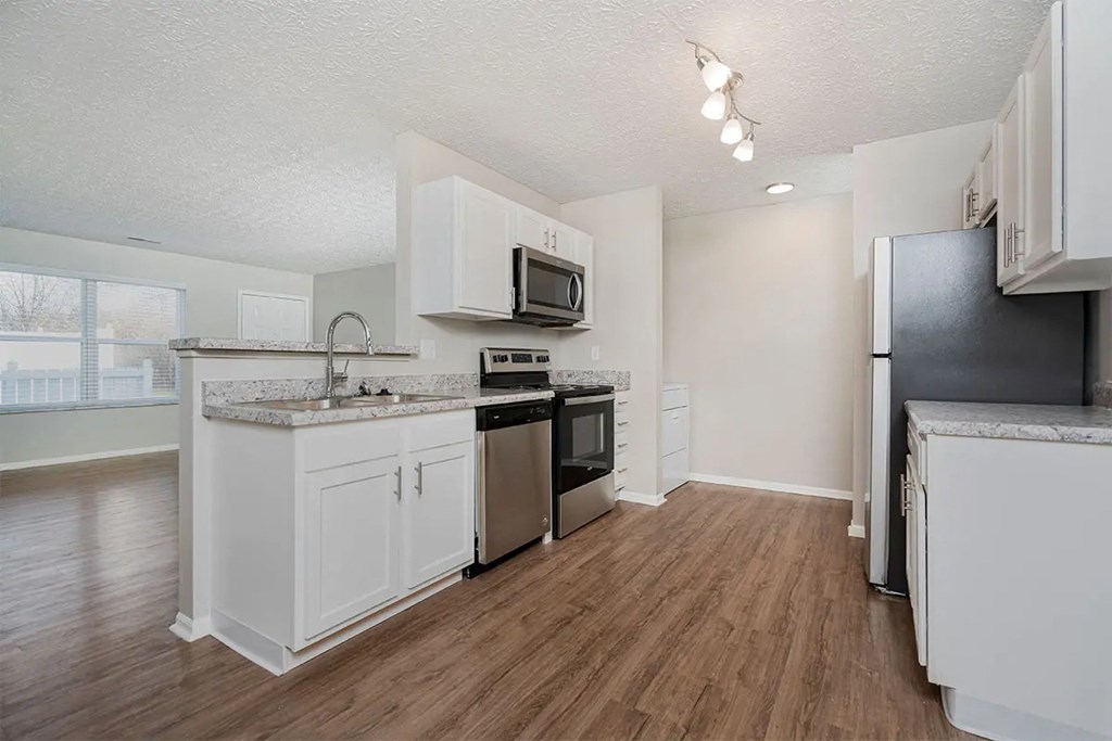 A kitchen with white cabinets and a black fridge.