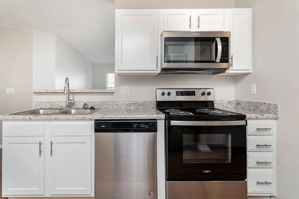 A kitchen with white cabinets and a granite countertop.