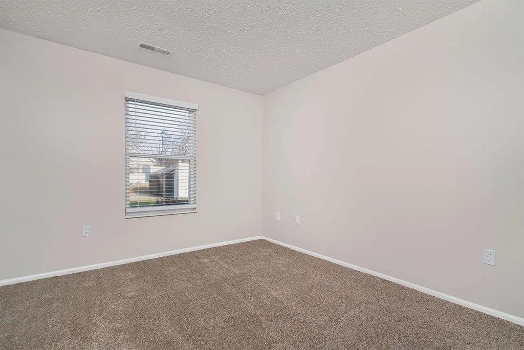 A room with a window and carpeted floor.