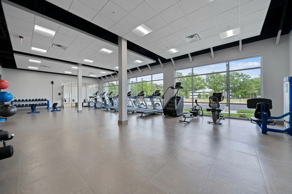 a gym with cardio equipment and windows on the side of a buildingat Metropolis Apartments, Glen Allen