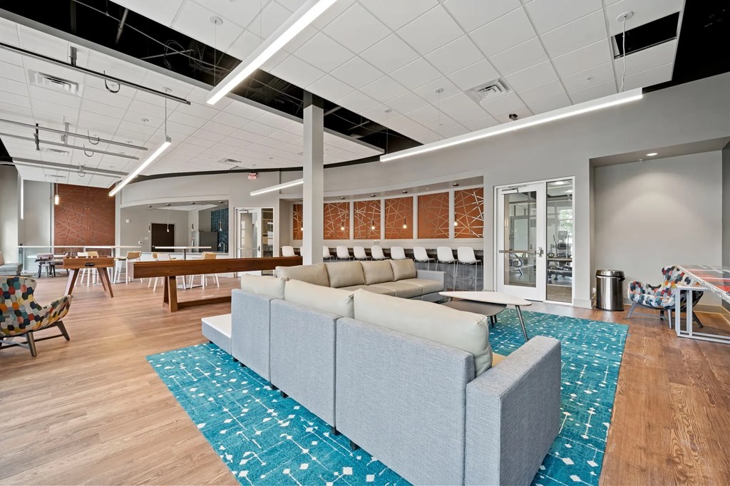 a lounge area with couches and chairs in a room with a tableat Metropolis Apartments, Glen Allen