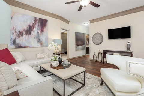 A living room with a white couch and a painting on the wall.