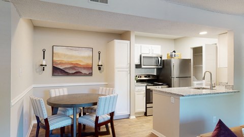 A kitchen with a table and chairs in front of a painting.