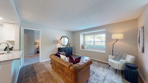 A living room with a brown couch and a white chair.