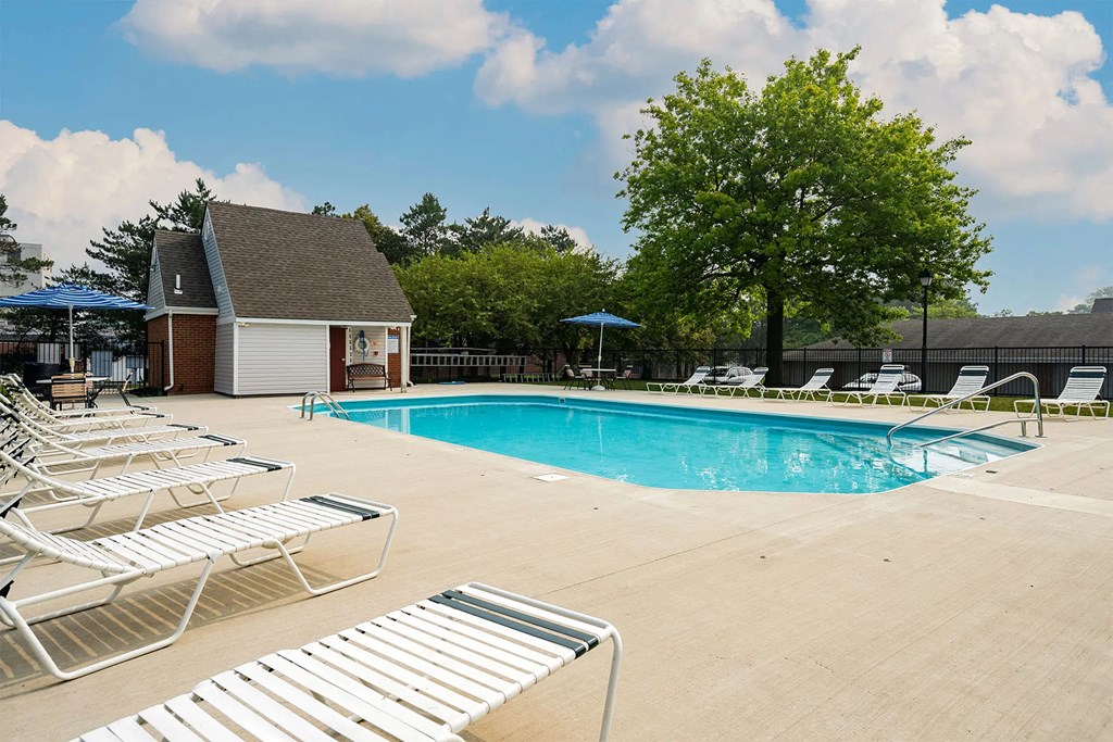 A pool with sun loungers and a building in the background.