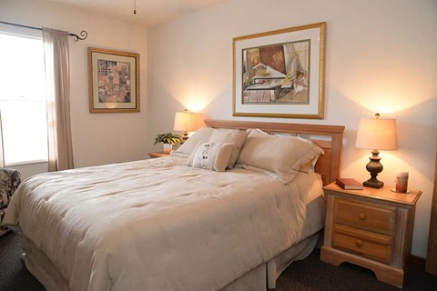 A bedroom with a large bed and a wooden nightstand.