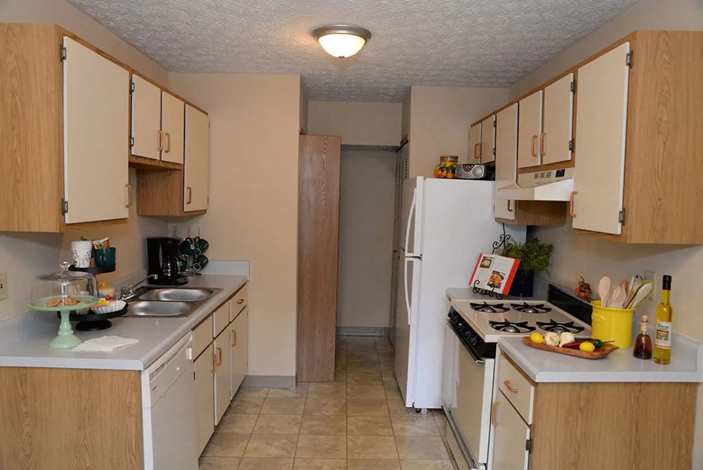 A kitchen with white appliances and wooden cabinets.