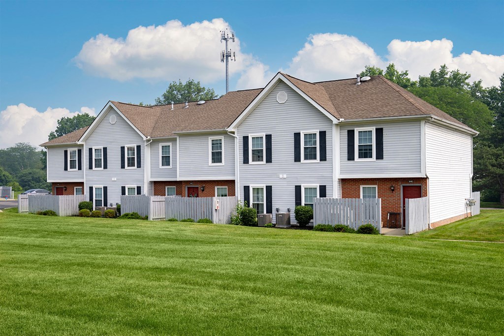 A white house with a brown roof and a fence.
